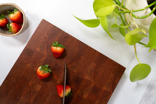 Cherry wood cutting board, square cherry cutting board, fresh cut strawberries, neon pothos