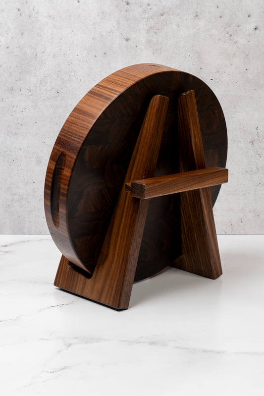 round end grain cutting board placed on a walnut cutting board stand with adjustable width, round butcher block made out of black american walnut, premium cutting board made 100% in USA by Square Root Studio