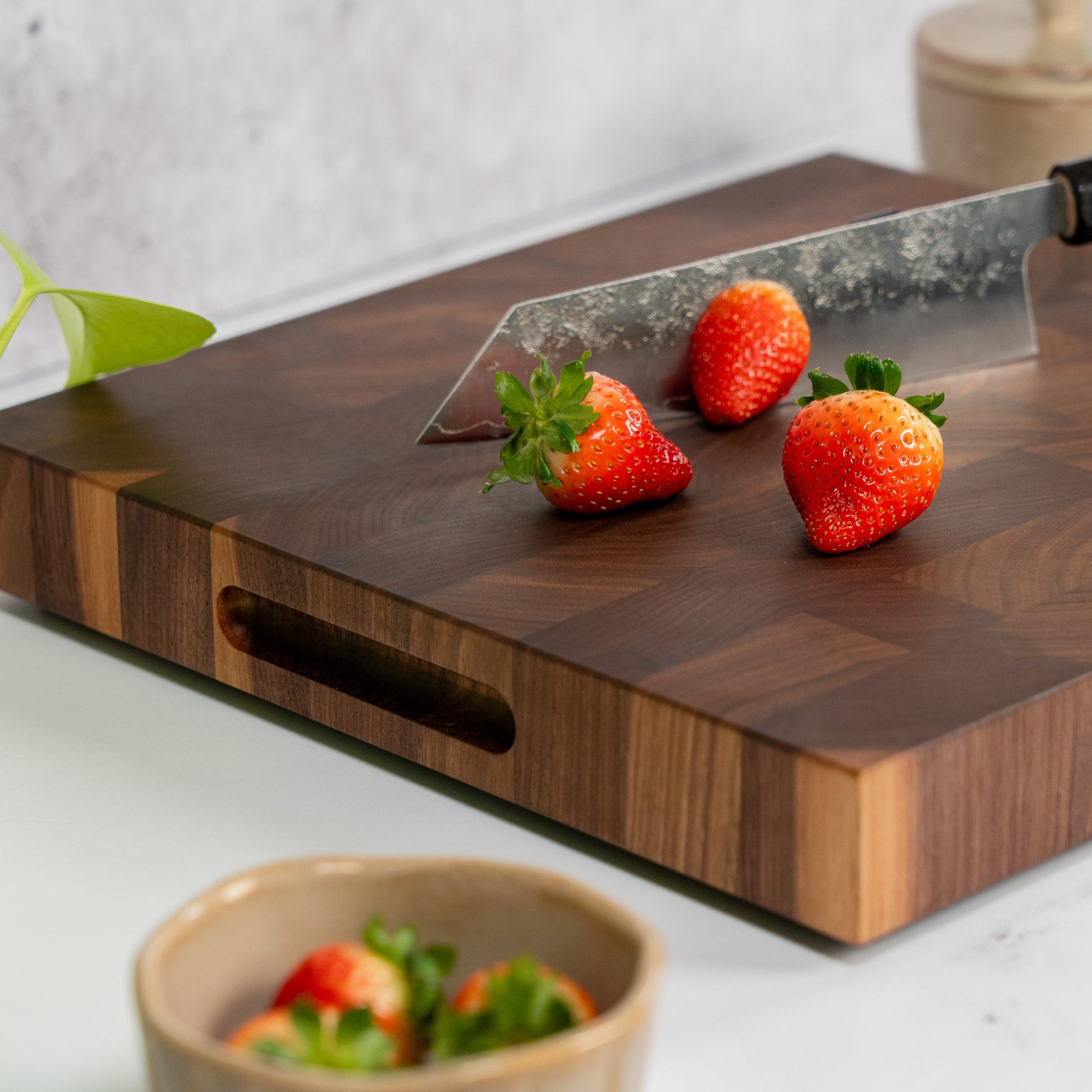 American Walnut cutting board on a marble kitchen counter top, square cutting board cherry wood, fresh strawberries, cutting board with handles