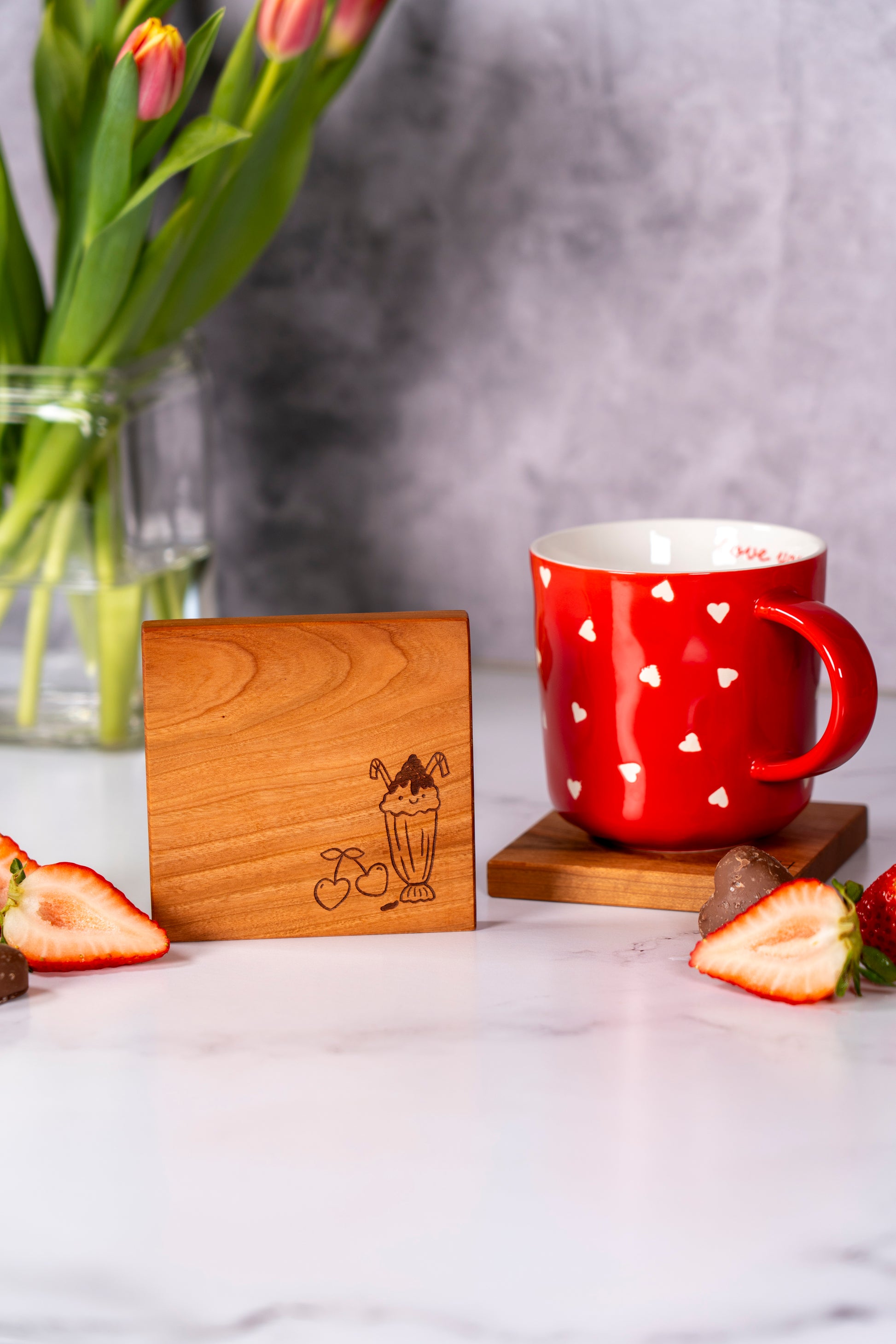 natural cherry wood coaster set, set of two coasters with lovely designs, heart themed laser engraving on natural wooden coasters, large coffee mug sitting on a coaster, red coffee mug, square 4x4 cherry wood coasters made by Square Root Studio in San Jose California