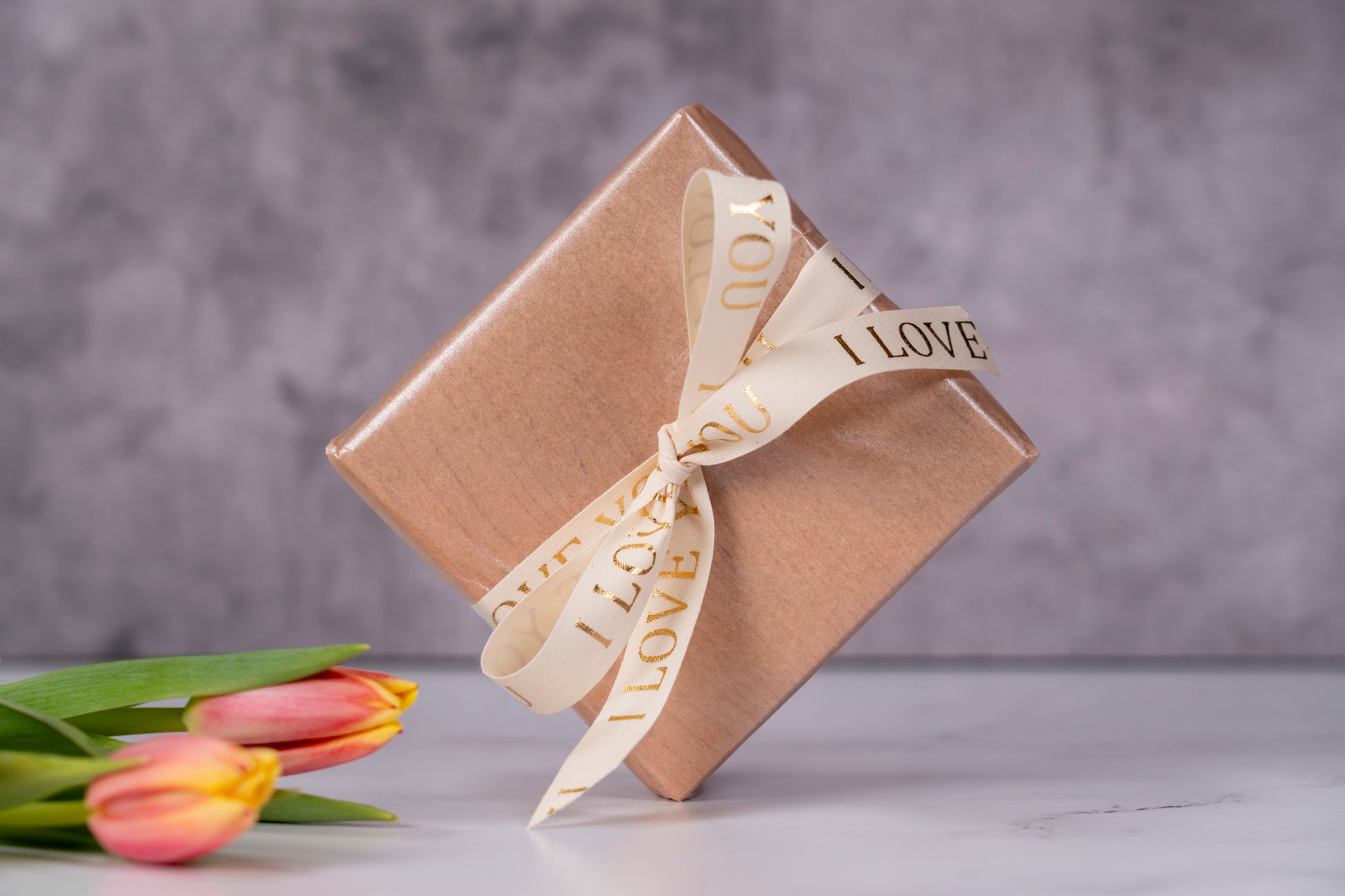 Premium gift wrapping, Unique gift set and packaging for girlfriend, fresh cut tulips, soft pink packaging with ivory bow tie with the text "I love you" written in golden letters, luxury gift options made in USA by Square Root Studio, a brand that focuses on a heathy lifestyle and sustainable home accessories and furniture pieces